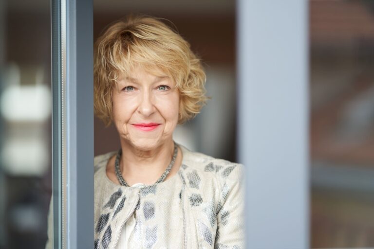 Kommunikationsberatung von Maria Lahmann hier im Portrait lächelnd am Fenster einer Terrassentür